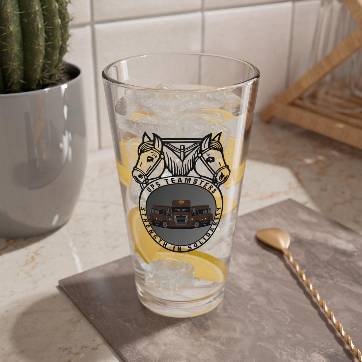 Clear 16oz UPS Teamsters pint glass with union emblem Teamster logo with UPS trucks on kitchen counter