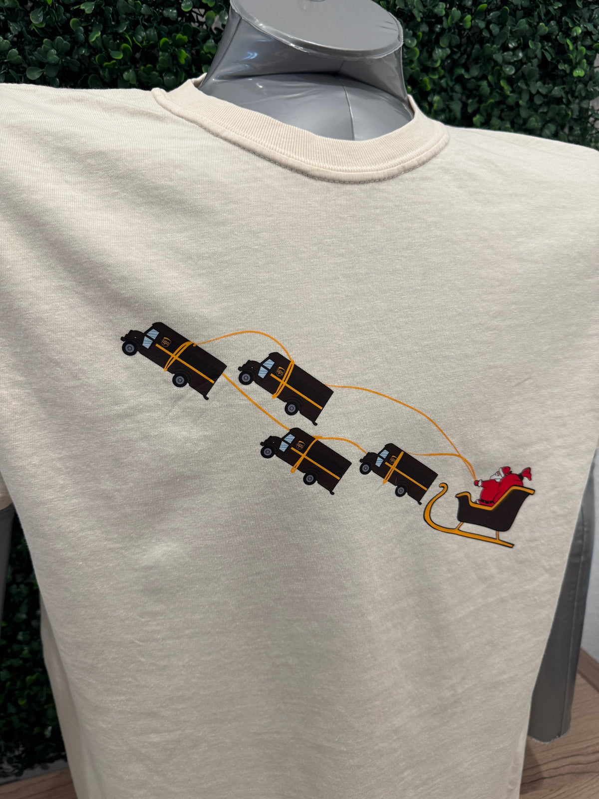 UPS Santa Peak Season Christmas Tee with Santa being pulled by UPS trucks design.